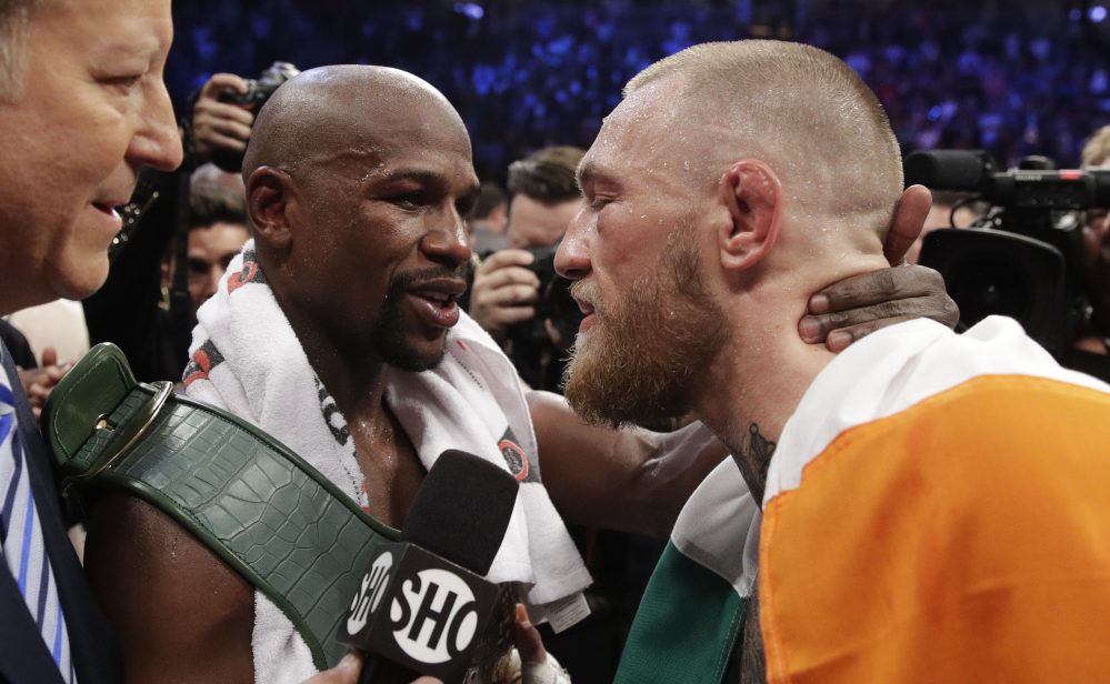 Floyd Mayweather Jr. embraces Conor McGregor after a fight that likely earned Mayweather more than $300 million and McGregor about $100 million.