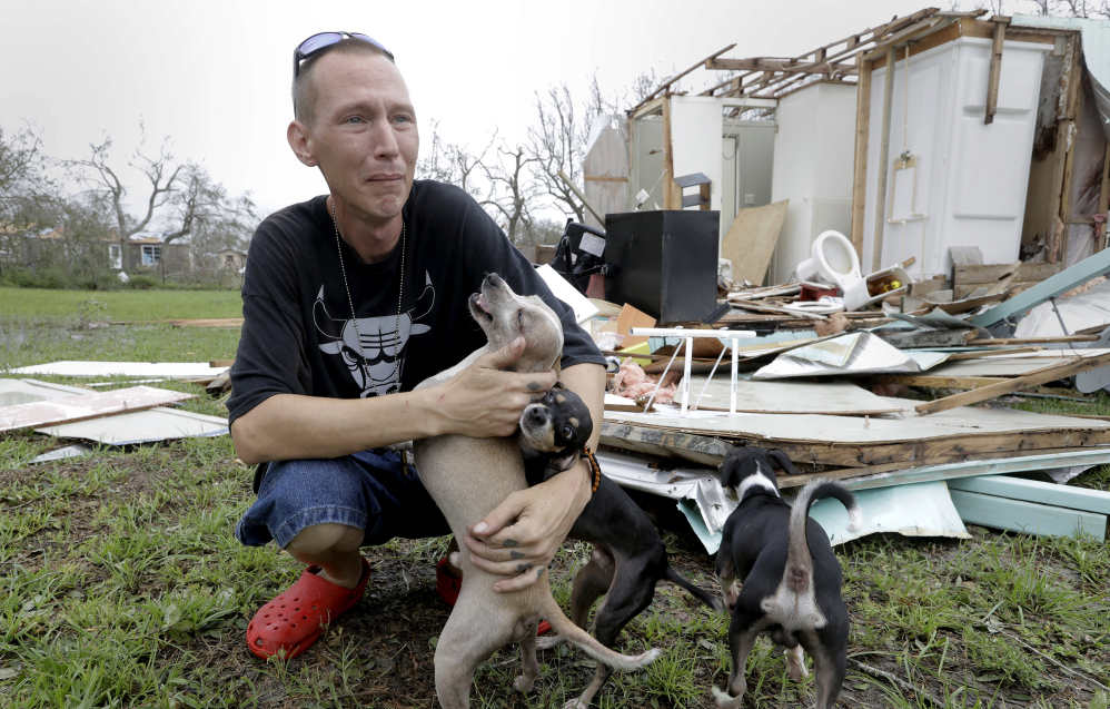 Sam Speights tries to keep back tears while holding his dogs and surveying the damage to his home in the wake of Hurricane Harvey on Sunday in Rockport, Texas. President Trump was tweeting the unfolding events Sunday.