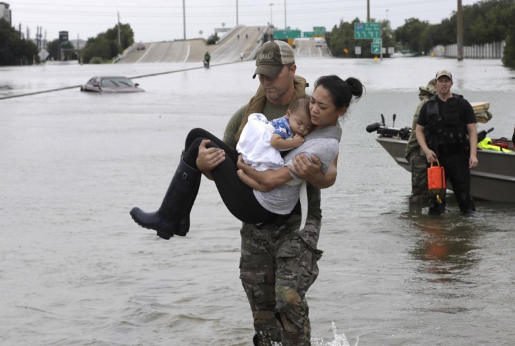 Houston Police SWAT officer Daryl Hudeck carries Catherine Pham and her 13-month-old son Aiden after rescuing them from their home surrounded by floodwaters from Tropical Storm Harvey Sunday in Houston. The remnants of Hurricane Harvey sent devastating floods pouring into Houston Sunday as rising water chased thousands of people to rooftops or higher ground.