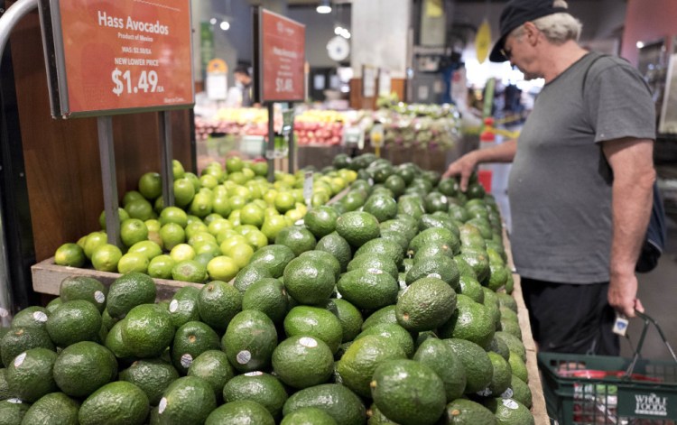A customer shops for avocados at a Whole Foods on Monday in New York. Cutting prices at Whole Foods shows that Amazon is serious about taking on competitors such as Wal-Mart, Kroger and Costco.