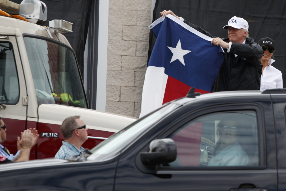President Trump, accompanied by first lady Melania Trump, holds up a Texas flag after speaking with supporters outside Firehouse 5 in Corpus Christi, Texas, on Tuesday following a briefing on Harvey relief efforts.