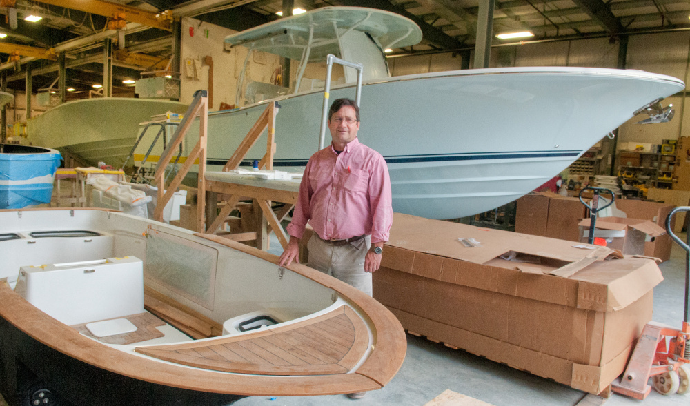 Southport Boats Vice President and General Manager George Menezes stands between a 16-foot Carbon Craft yacht tender, front, and a 33-foot Southport boat in Augusta on Tuesday, the day an expansion and sale to the principals of Carbon Craft were announced.
