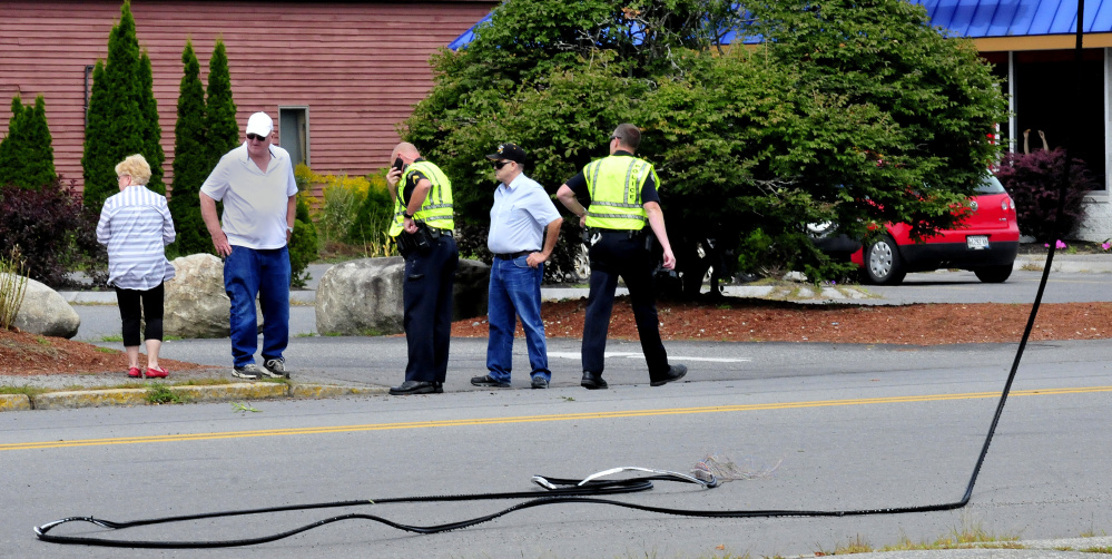 Waterville police interview witnesses near the site where they say two trucks hit and eventually snapped a communications wire across College Avenue in Waterville on Tuesday.