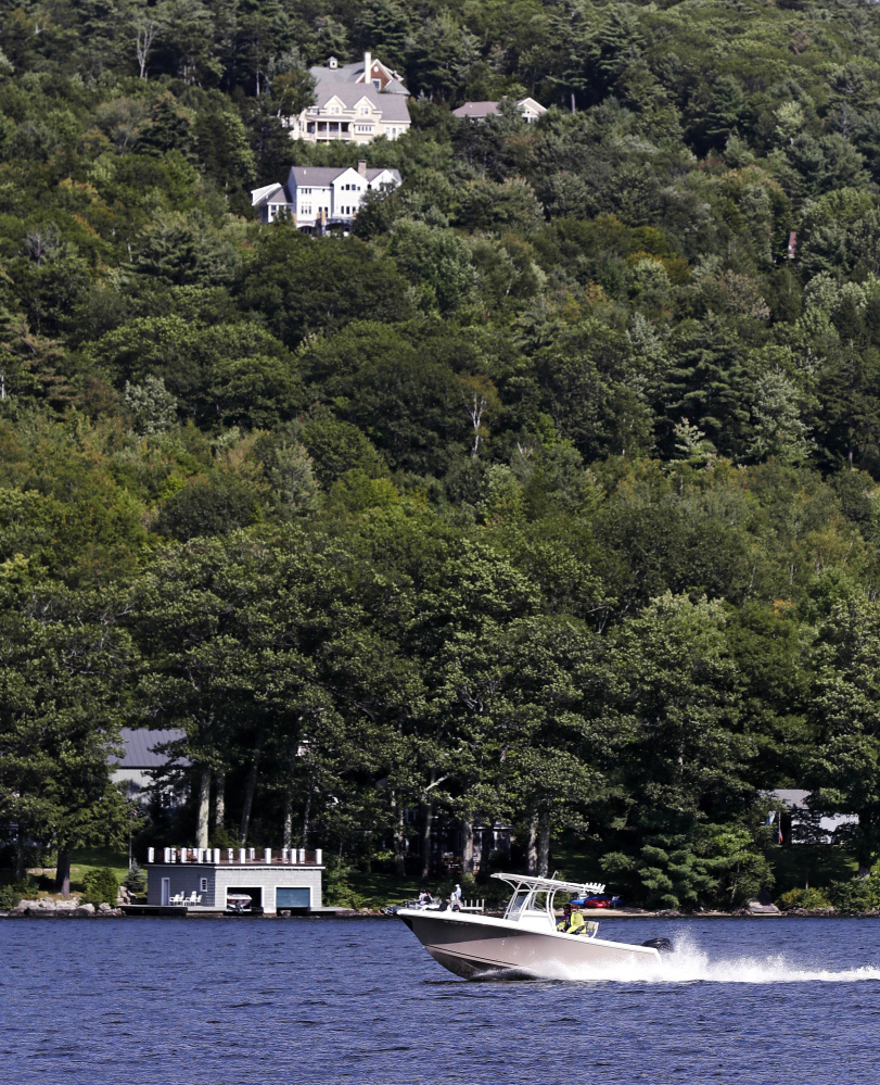 A power boat passes homes built on a hill over looking Lake Sunapee in Newbury, N.H.  Lake residents say it is unfair to suggest they are against access to poor outsiders.