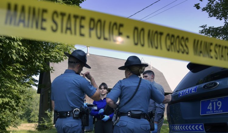 Maine State Police troopers and detectives confer Monday outside a residence in Litchfield where a man was reportedly shot.