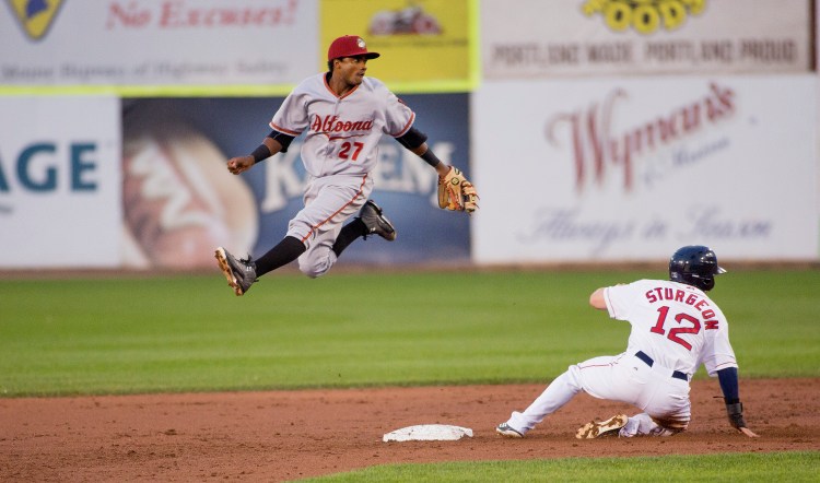 Altoona’s Pablo Reyes jumps up in the air as he throws the ball to first as Cole Sturgeon of the Sea Dogs slides into second in Tuesday night’s game at Hadlock Field. The Curve beat the Sea Dogs, 5-3.