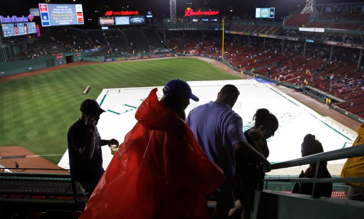 Fans leave Fenway Park after Wednesday's game between the Red Sox and Cleveland Indians was postponed due to heavy rain and thunderstorms.
