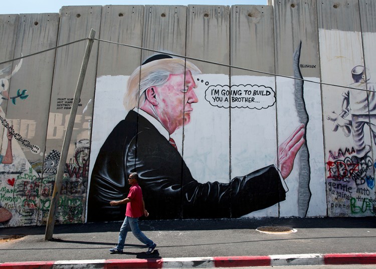 A mural resembling the work of the elusive artist Banksy depicts President Trump wearing a Jewish skullcap  on Israel's West Bank separation barrier in the city of Bethlehem.