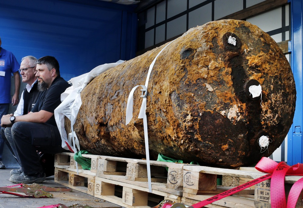 Bomb disposal experts Dieter Schwaetzler, left, and Rene Bennert sit next to a 1.8-ton World War II-era  bomb after they defused it in the German financial capital of Frankfurt on Sunday. More than 60,000 people had to be evacuated. Associated Press/Michael Probst