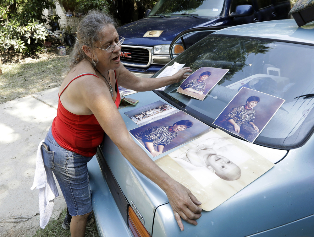 Pam Murray places a damaged baby picture of her son, Rob, on a trunk of a car to dry out Sunday while cleaning out her mother's home, which was destroyed by floodwaters in the aftermath of the Category 4 Hurricane Harvey in Spring, Texas.