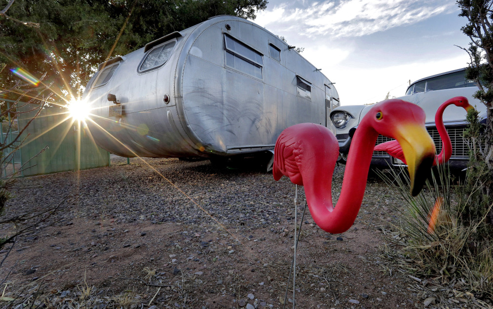 The sun sets behind a 1950 Hughes Spartan travel trailer complete with pink flamingo and vintage El Dorado Cadillac at the Shady Dell trailer court in Bisbee, Ariz. The trailers are for rent, like hotel rooms, and songs from 1950s vinyl records play over a loudspeaker.
