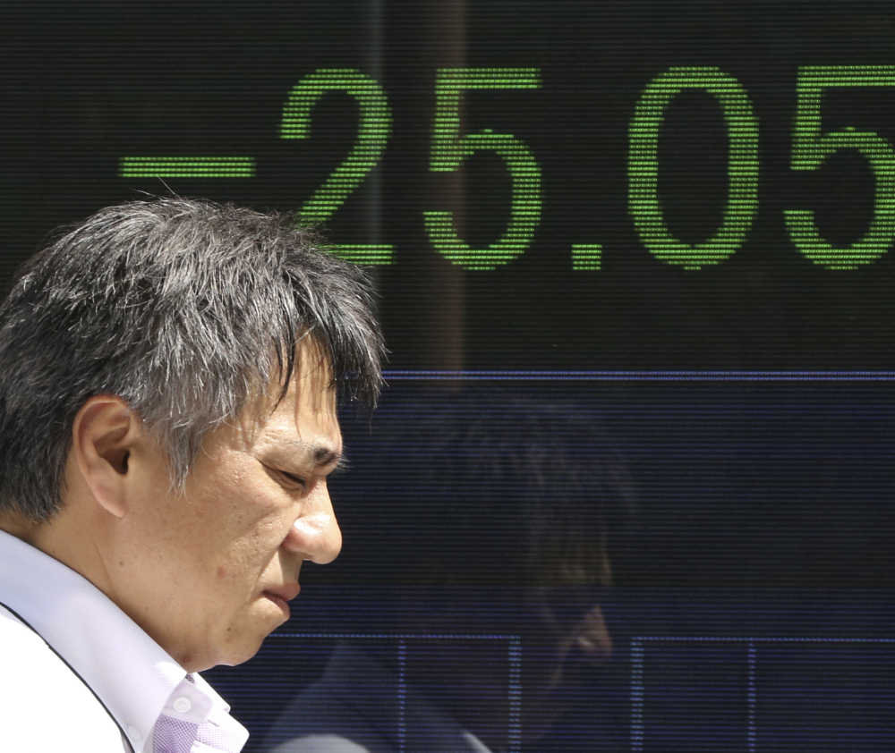 A man walks by an electronic stock board of a securities firm in Tokyo. Asian shares including Japan's Nikkei index were mostly lower Monday, following the news that North Korea said it successfully tested a hydrogen bomb.