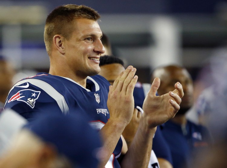 Rob Gronkowski applauds his teammates while watching from the sideline. Grownkowski seems to be a little more serious about his career with the Patriots as he hopes to play a full slate of games.  Winslow Townson/Associated Press