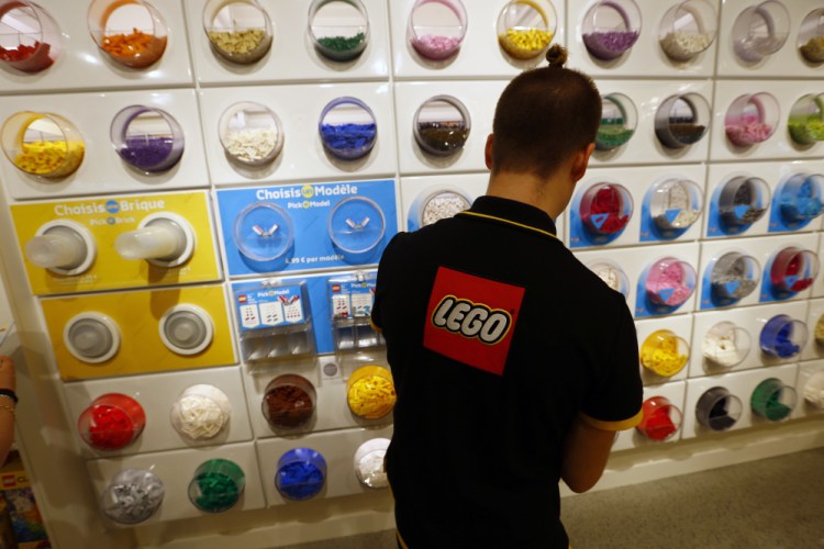 A worker sorts Legos in a Paris store. The company's revenue dropped 5 percent in the first half of this year, to $2.4 billion, with weaker demand in the U.S. and Europe.