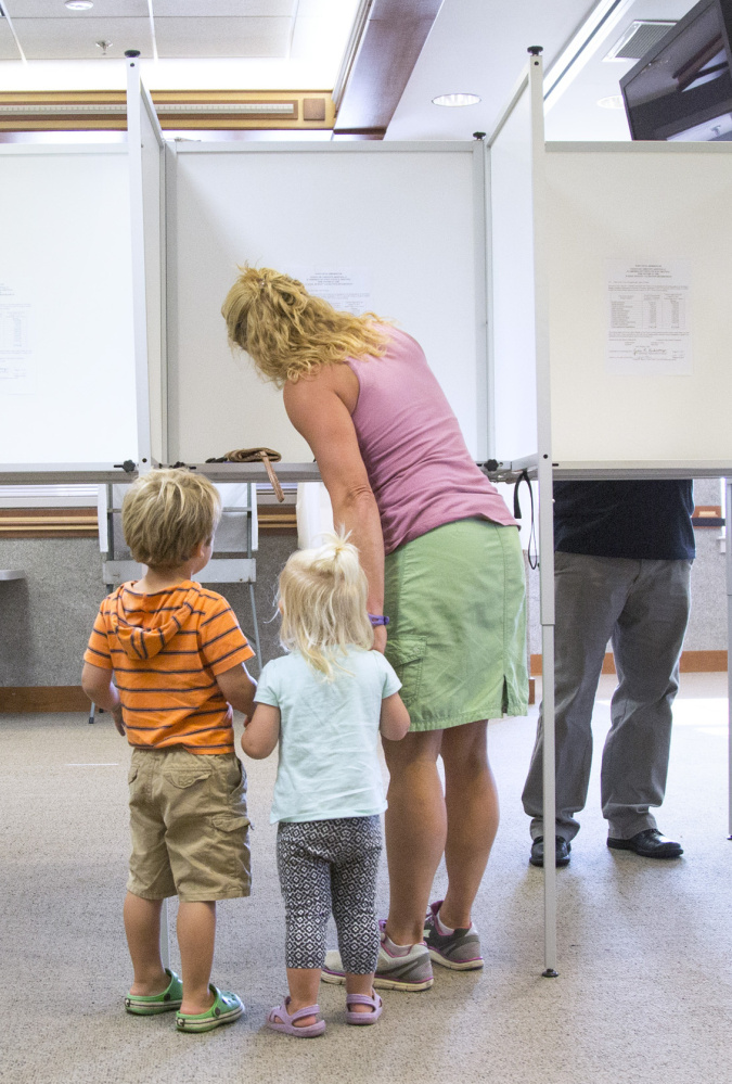 Scarborough resident Kelly Pietrzak casts her vote on the school budget with her children Marek, 3, left, and Kaja, 2, at the town hall on Tuesday.