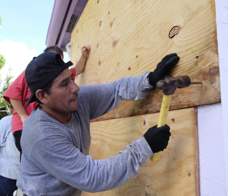 As Irma closes in, Pedro Reimundo nails plywood shielding on a home in Florida City, Fla., on Friday.