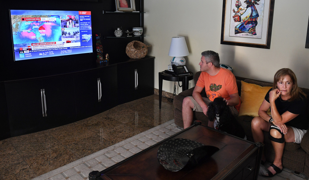 Adam Fischer watches coverage of Hurricane Irma on Friday at the home of his mother-in-law, Jan Bell Pollack, less than a mile from Biscayne Bay. The Pollacks – including Penny the poodle – plan to ride out the storm at home.