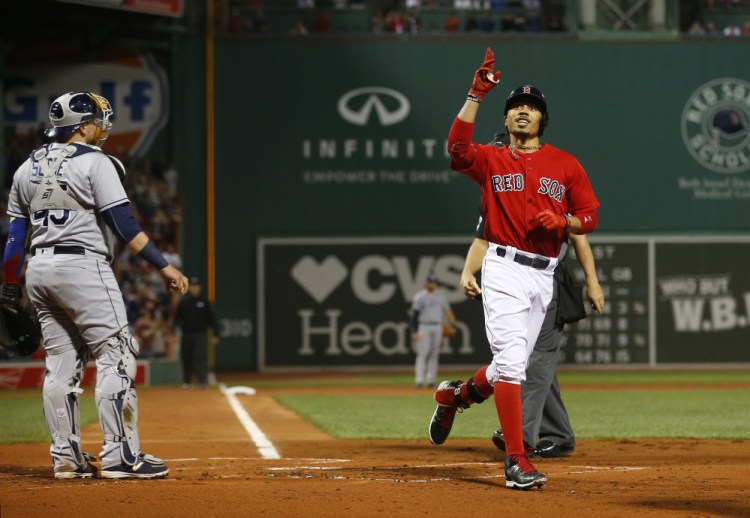 Mookie Betts points skyward after hitting a three-run home run as Tampa Bay Rays catcher Jesus Sucre watches in the first inning Friday night at Fenway Park.