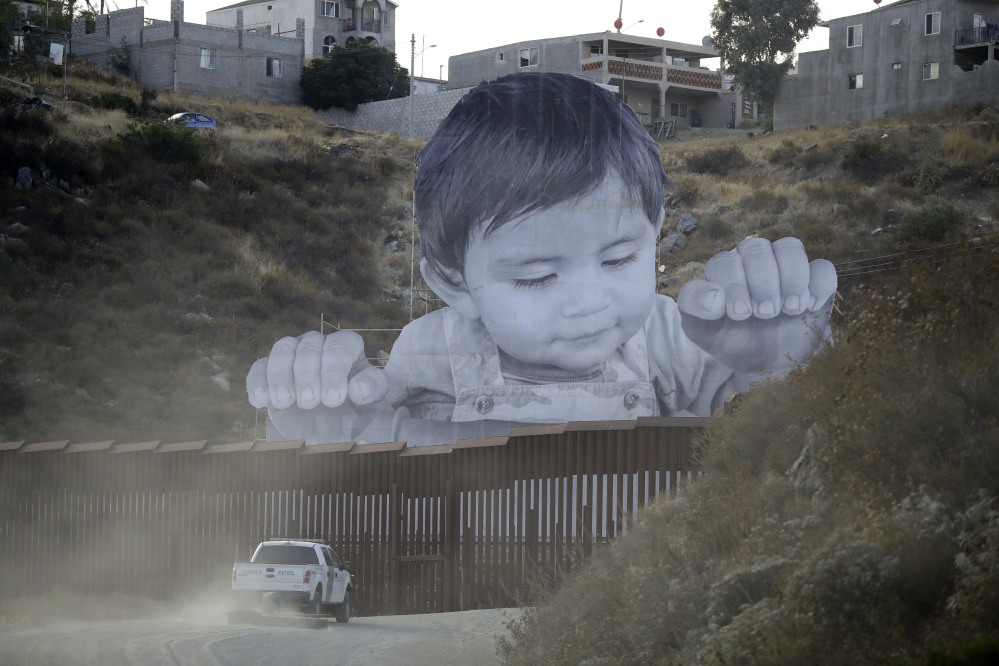 A 65-foot-tall photo of a Mexican boy, mounted on scaffolding in Tecate, Mexico, appears to look over a section of border wall on the California border Friday.

