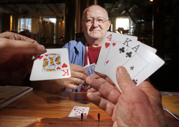 Eldon Woodman lays down a king of hearts while playing cribbage with Ken Capron at Banded Horn Brewing Co. in Biddeford on Thursday. Capron lobbied to get state gaming regulations changed to simplify the organizing of charitable cribbage tournaments. The resulting Great State of Maine Cribbage Tournament will play out at locations around the state this month.