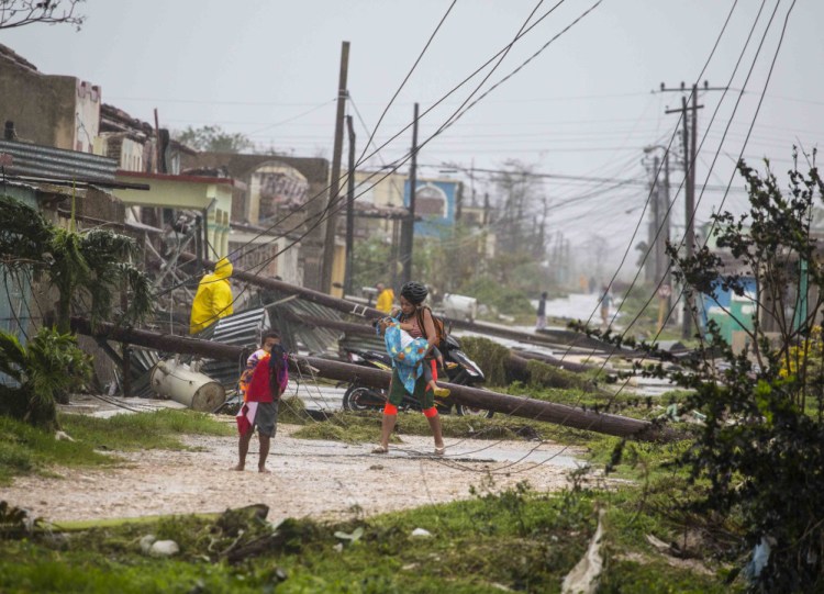 Residents walk near downed power lines felled by Hurricane Irma in Caibarien, Cuba, on Saturday. There were no reports of deaths or injuries after heavy rain and winds from Irma lashed northeastern Cuba.
