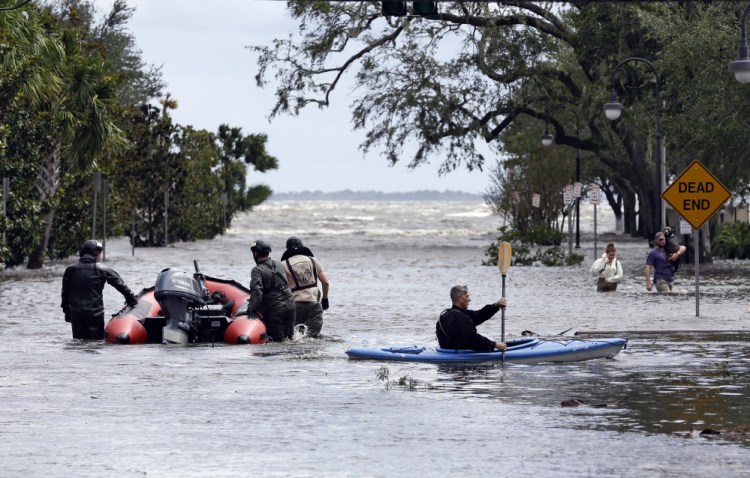 Rescue workers search a neighborhood for flood victims Monday as a man on a kayak paddles down the street after Hurricane Irma brought flood waters to Jacksonville, Fla.