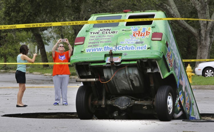 Residents on Monday take photos of a van in a sinkhole that opened up at the Astor Park apartment complex in Winter Springs, Fla., during Hurricane Irma's passing through central Florida.