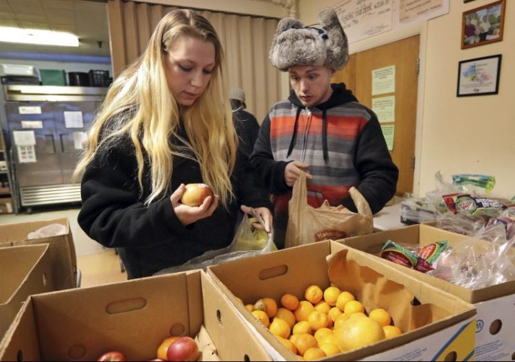 Sunny Larson, left, and Zak McCutcheon pick produce while gathering provisions to take home from the Augusta Food Bank, which is serving a record-breaking number of families – over 400 a month. Food pantries have become a regular source of nutrition for many, not just a stopgap.