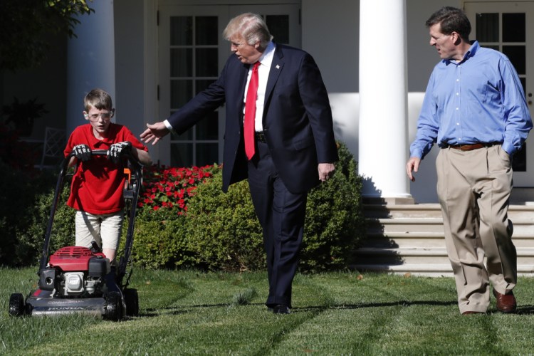 Frank Giaccio, 11, of Falls Church, Va., left, is accompanied by President Trump as he mows the lawn of the Rose Garden, Friday at the White House with his father Greg Giaccio.