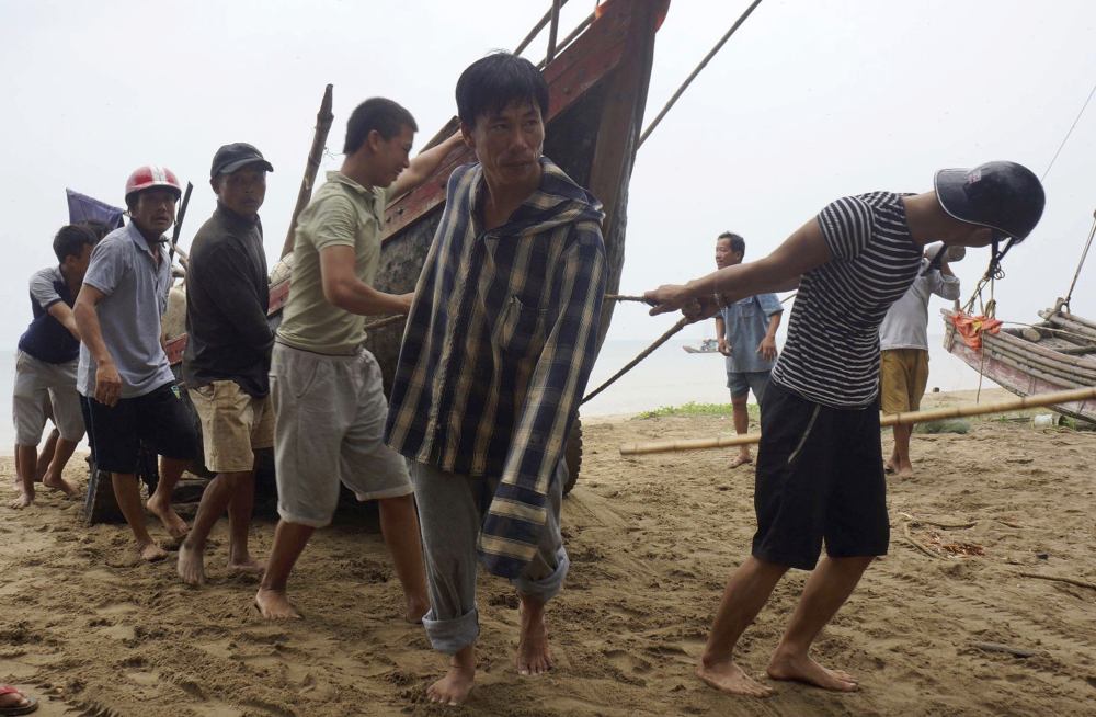 Vietnamese villagers move a fishing boat on shore in northern Thanh Hoa province Thursday, ahead of Typhoon Doksuri, which killed four people and injured 10 others.