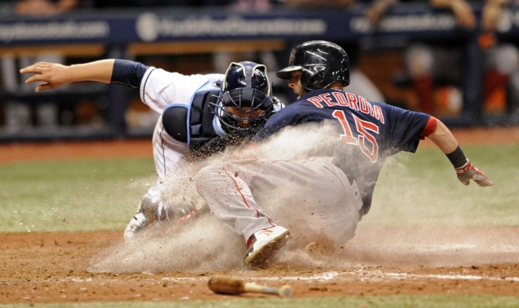 Boston's Dustin Pedroia slides by the tag from Tampa Bay catcher Jesus Sucre to score on Keith Moreland's RBI single during the 15th inning early Saturday morning in St. Petersburg, Fla. The Red Sox won 13-6 to stay three games up in the AL East.