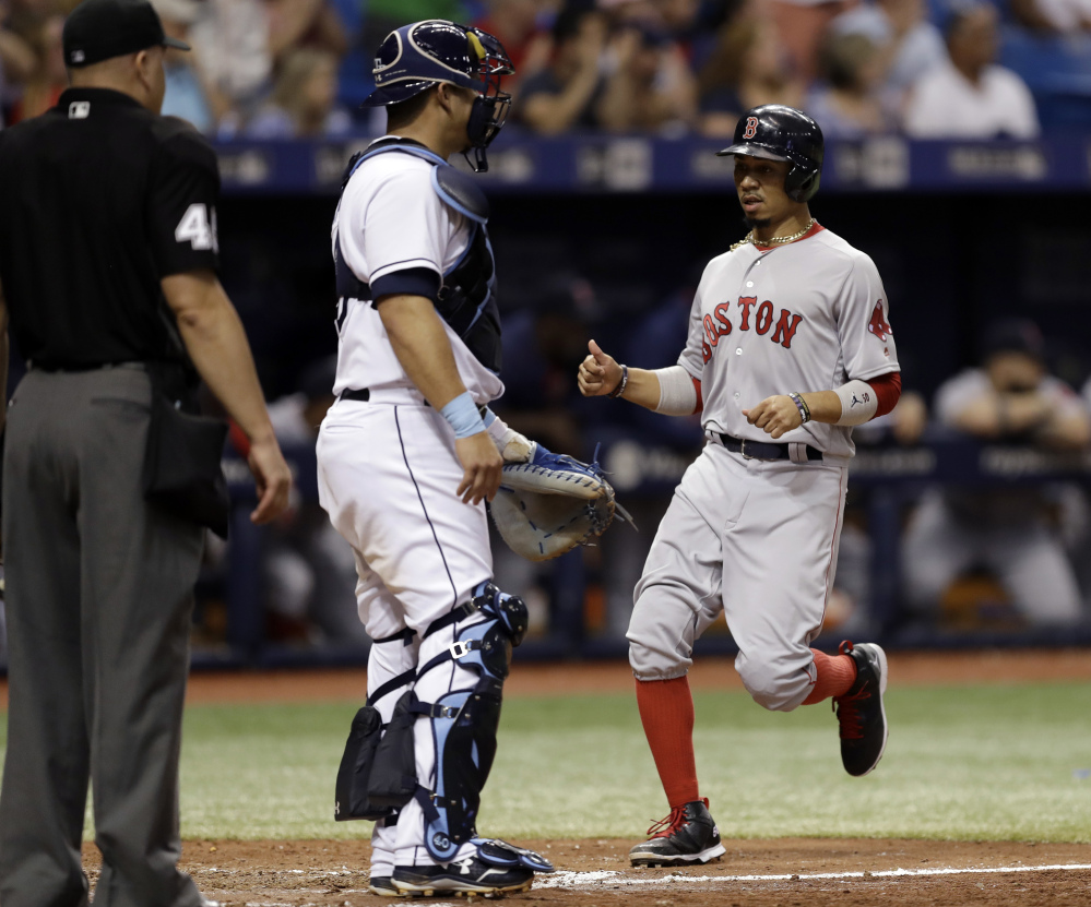 Boston's Mookie Betts scores in front of Tampa Bay Rays catcher Wilson Ramos and home plate umpire Jeff Nelson on a double by Rafael Devers during the sixth inning of Saturday's game in St. Petersburg, Fla. The Red Sox won, 3-1.