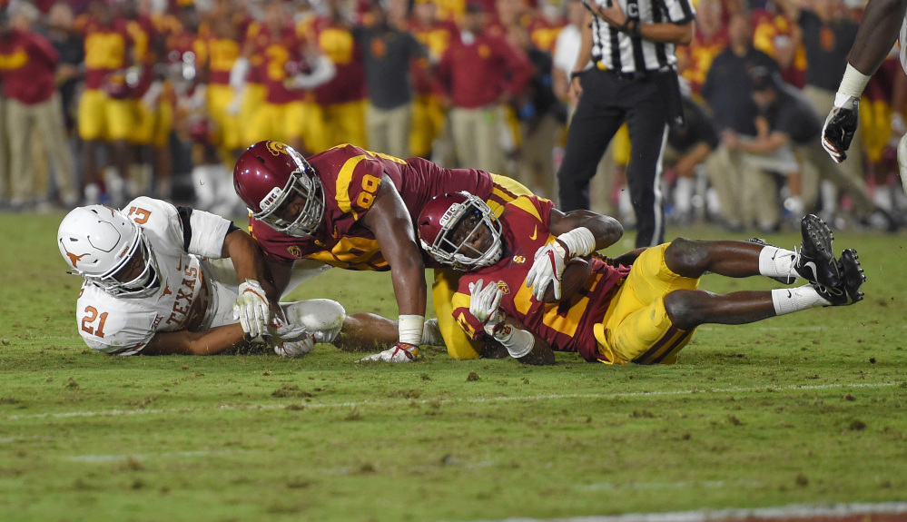 USC cornerback Ajene Harris, right, recovers a fumble by Texas as Texas running back Kyle Porter, left, and defensive lineman Christian Rector fall during the second overtime Saturday night in Los Angeles. USC won 27-24 in two overtimes.