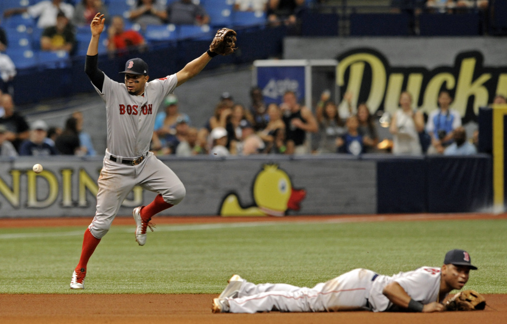 Boston's Xander Bogaerts, left, and Rafael Devers cannot stop a ground ball single hit by Tampa Bay's Evan Longoria that drove in Jesus Sucre from third base during the fifth inning of the Red Sox' 3-2 loss Sunday in St. Petersburg, Florida.