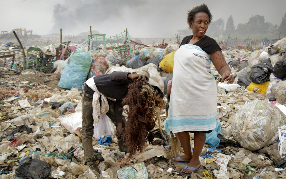 A man who scavenges hairpieces from the piles of rubbish at the Dandora municipal dump offers them for sale to Winnie Wanjira, 31, a hairdresser in the slum across the river.