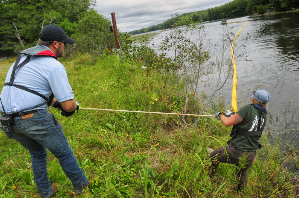 After somebody on a boat tossed it to them, Tim House, a trainer from Moran Environmental Recovery, left, and Tiffany LaClair, of the Department of Environmental Protection, pull the rope on a containment boom onto shore Tuesday during a training exercise in the Kennebec River off Swan Island.