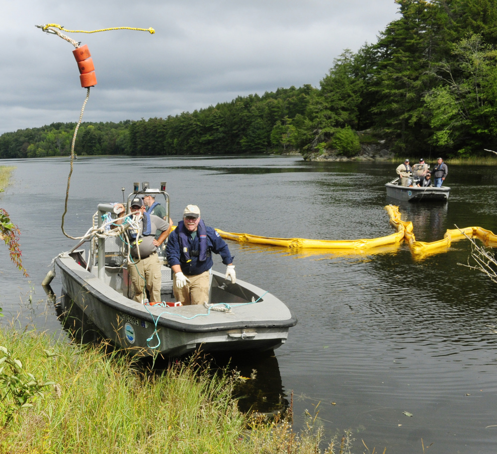 Department of Environmental Protection Division of Response Services staffer Robert Williams, center, tosses the line from a containment boom to a co-worker on shore on Tuesday during a training exercise in the Kennebec River off Swan Island.