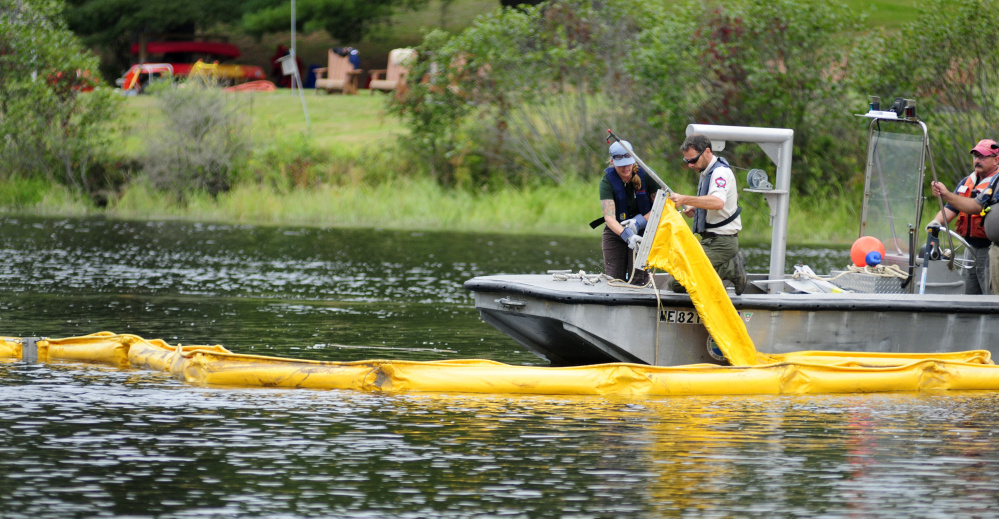 Tiffany LaClair, of the Dept. of Environmental Protection's Division of Response Services, left, and John Pratte, biologist for the Dept. of Inland Fisheries & Wildlife, pull the end of a containment boom Tuesday during a training exercise in the Kennebec River off Swan Island.