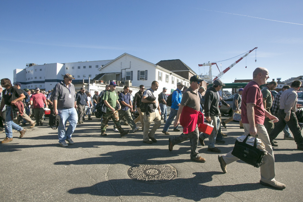 Workers leave the main gate after first shift ends at Bath Iron Works last September.