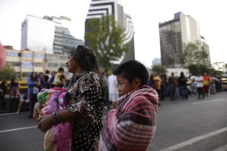 People stand in the street after hearing an earthquake alarm in Mexico City on Saturday. A strong aftershock rolled through Mexico City on Saturday morning, swaying buildings and sending some people running into the street.