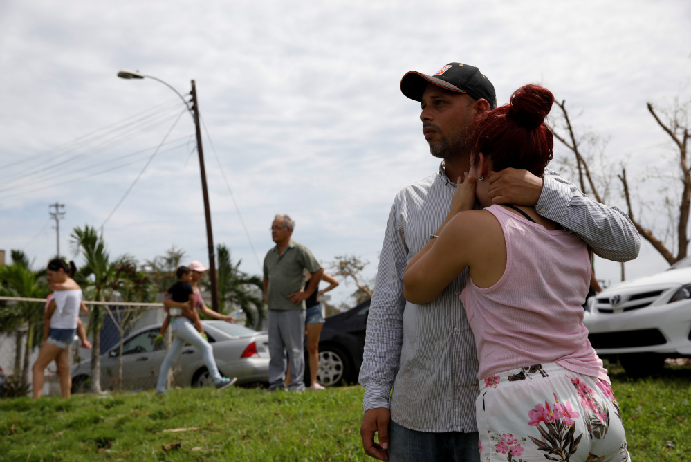 Local residents watch water flooding the road near the Lake  Guajataca dam. Thousands of people are awaiting evacuation.