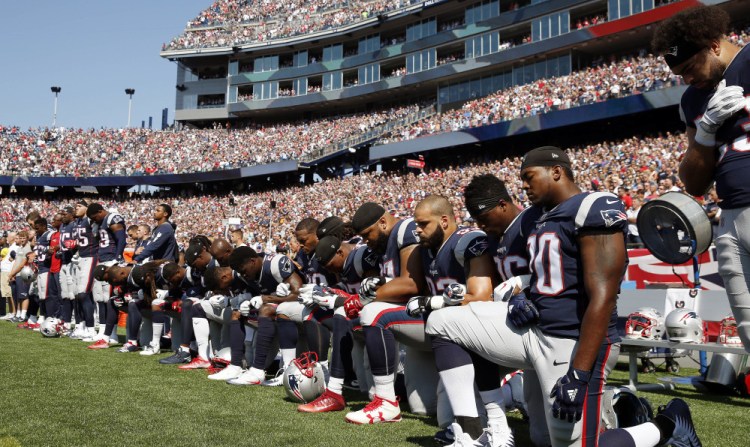 Several New England Patriots players kneel during the national anthem before an NFL game against the Houston Texans on Sunday in Foxborough, Mass.