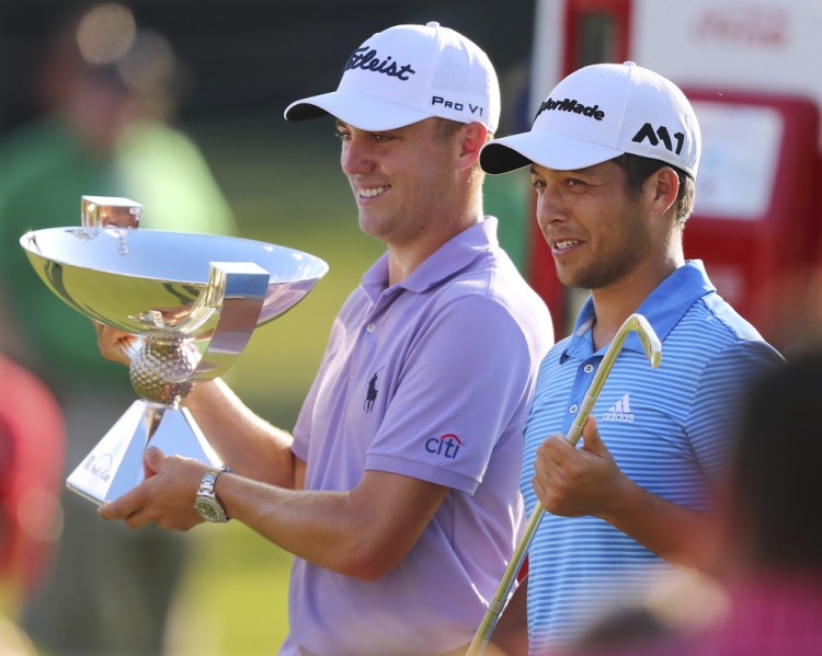 Justin Thomas, left, holds the trophy after winning the Fedex Cup, as he stands with Xander Schauffele who holds the trophy after winning the Tour Championship on Sunday in Atlanta.