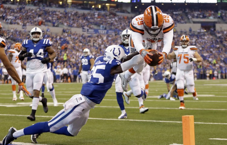 Browns running back Duke Johnson dives over Colts defensive back Pierre Desir to score a touchdown Sunday in Indianapolis. Cleveland lost, 31-28.