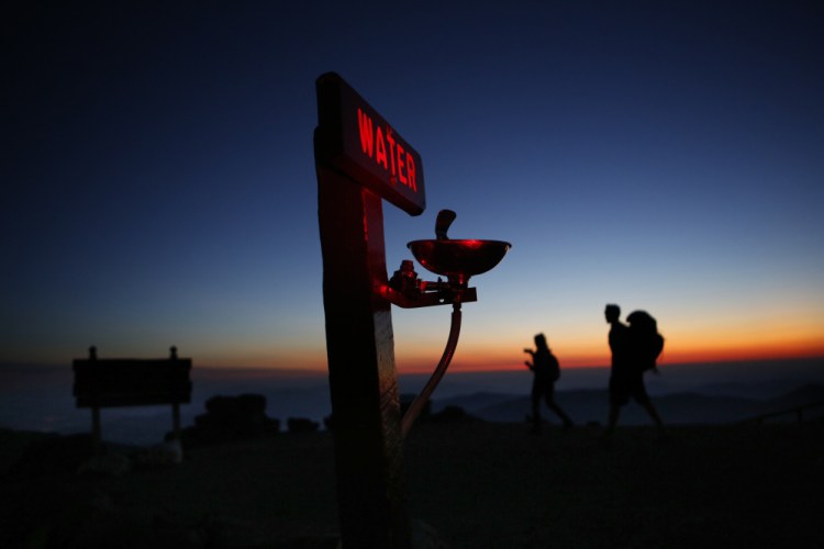 Quincy Andrews, left, and Josh Fournier, both of Meredith, N.H., arrive at dawn Sunday at the summit of Mount Washington, N.H., where a water fountain awaits visitors to New England's highest peak. The weather observatory on the summit recorded a record daily temperature high Sunday when the mercury hit 65 degrees, the highest ever for a Sept. 24.
