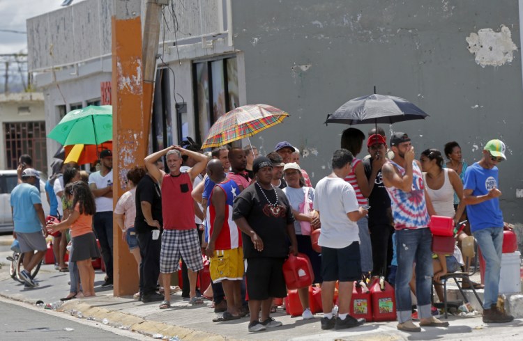 In the aftermath of Hurricane Maria, residents of San Juan, Puerto Rico, line up to get fuel from a gas station on Monday. The U.S. ramped up aid amid criticism that it wasn't doing enough.