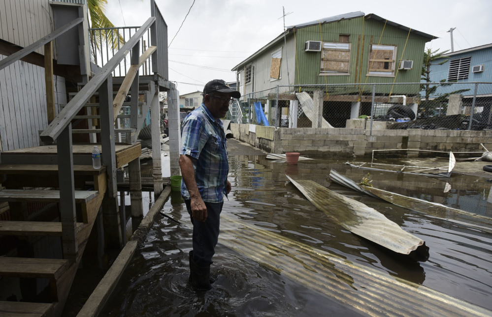 Hector Rosa walks through a flooded area of Juana Matos, Puerto Rico, on Wednesday.
At left, Christian Mendoza counts money in the aisle of a San Juan supermarket, where he had hoped to buy bottled water but found only cans of juice Monday. Widespread communication failures have complicated relief efforts on the island territory of 3.4 million people.