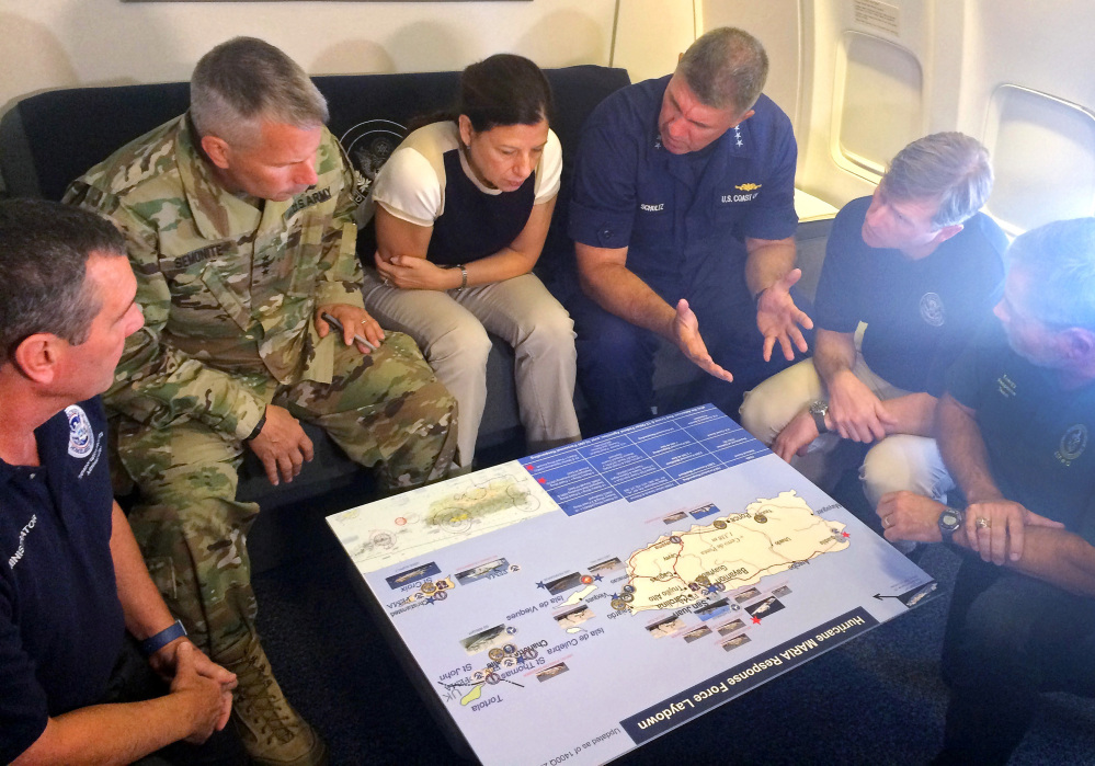 Acting Homeland Security Secretary Elaine Duke, center, is briefed on the Hurricane Maria response during a flight to Puerto Rico on Friday. The administration has defended its handling of the disaster, but on Friday that mayor of San Juan said, "We are dying and you are killing us with the inefficiency and the bureaucracy."