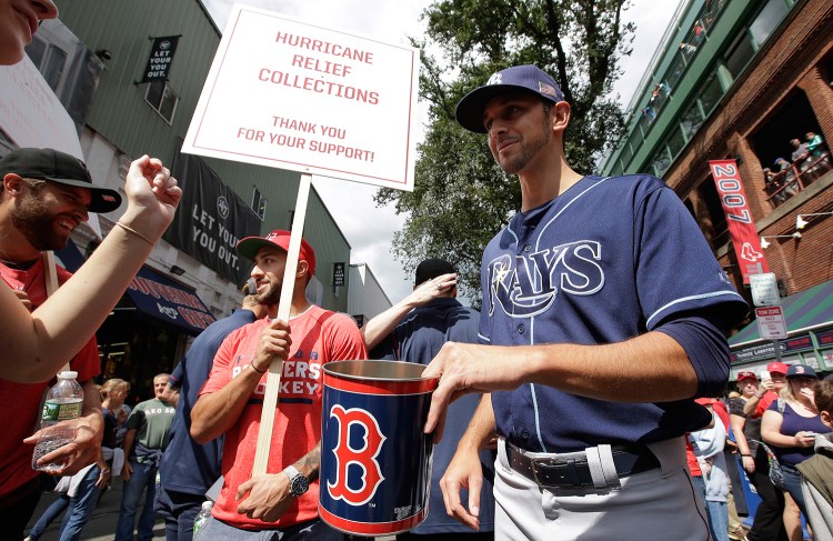 Florida Panthers' Vincent Trocheck, center left, holds a sign as he Tampa Bay Rays' Steve Cishek, right, collect donations outside Fenway Park in Boston for relief efforts after Hurricane Irma, before a baseball game between the Rays and the Boston Red Sox on Sunday in Boston. 