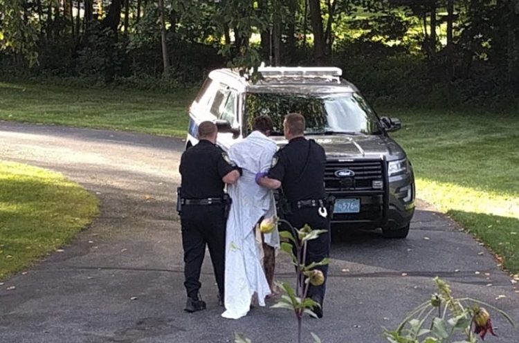 Police officers take Orion Krause, covered in a white sheet, to a police vehicle in Groton, Mass., on Sept. 8. 